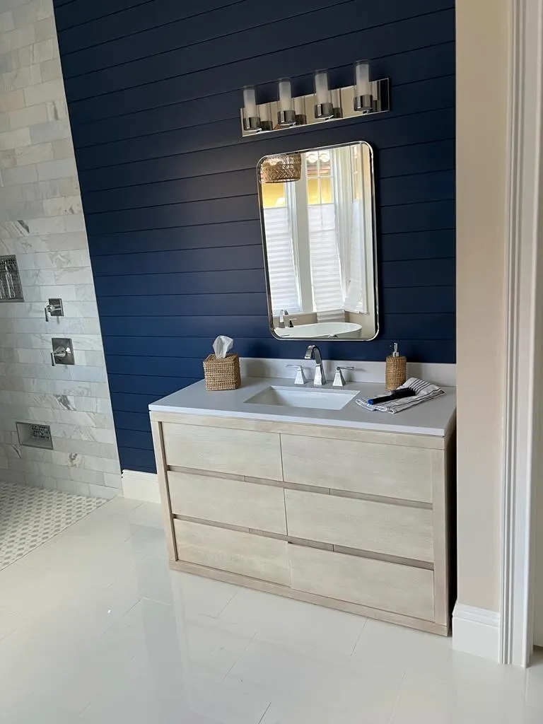 Elegant bathroom with navy blue shiplap accent wall, white floating vanity, rectangular mirror, and modern fixtures